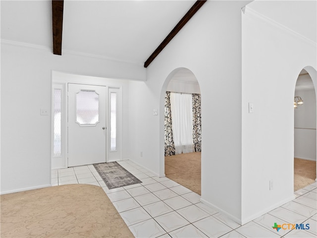 entrance foyer featuring arched walkways, light tile patterned floors, vaulted ceiling with beams, light colored carpet, and baseboards