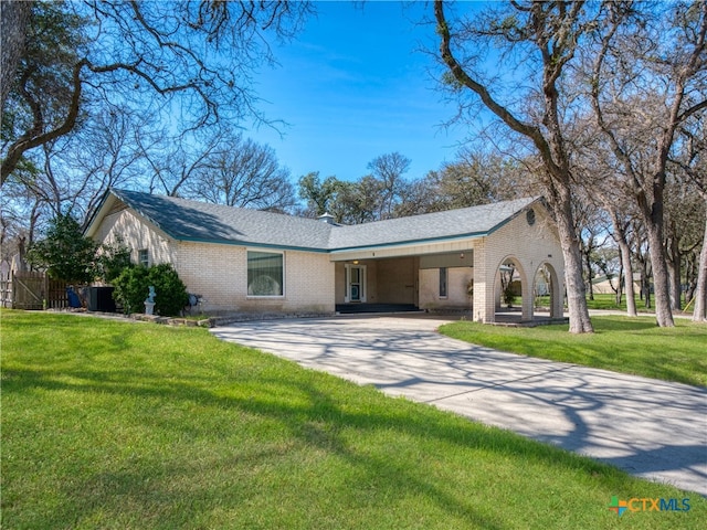 ranch-style home featuring driveway, a front lawn, a shingled roof, and brick siding