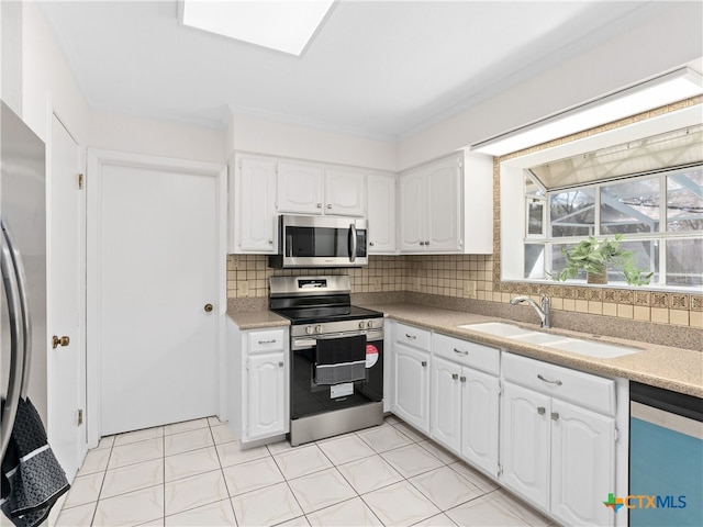 kitchen featuring tasteful backsplash, light countertops, appliances with stainless steel finishes, white cabinetry, and a sink