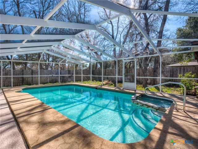 view of swimming pool featuring a patio area, glass enclosure, a fenced backyard, and a pool with connected hot tub