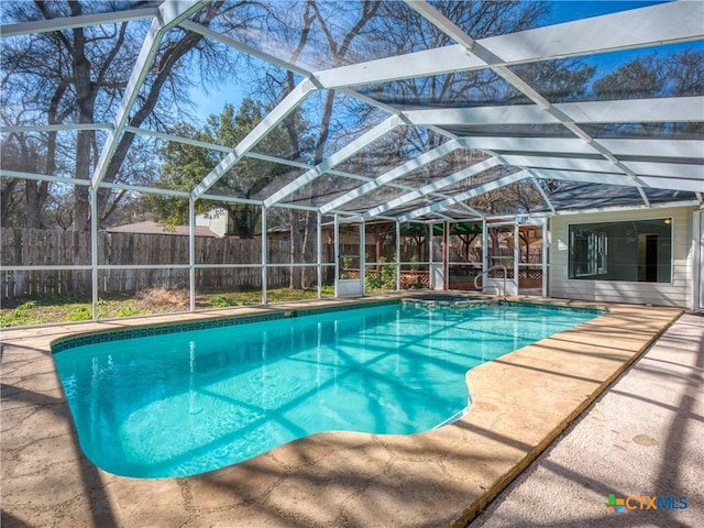 view of pool featuring glass enclosure, a patio, a fenced backyard, and a fenced in pool