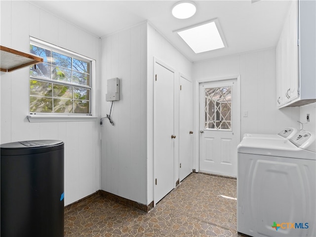 washroom with cabinet space, stone finish flooring, a skylight, and washing machine and clothes dryer