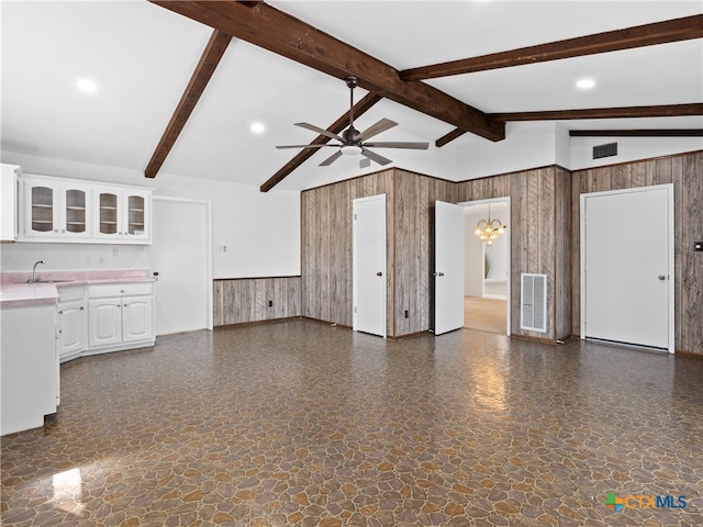 kitchen featuring open floor plan, wood walls, a sink, and visible vents