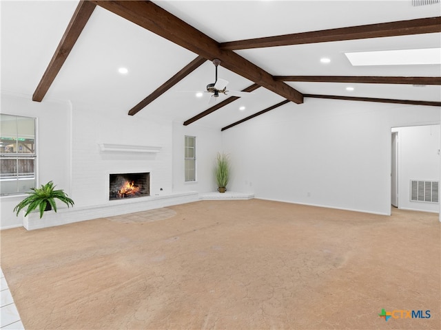 unfurnished living room featuring ceiling fan, light colored carpet, visible vents, a lit fireplace, and lofted ceiling with skylight