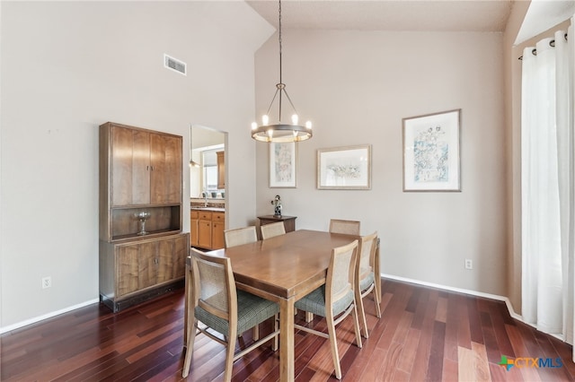 8302 Dove Valley Cv, Austin, TX 78729 - dining area featuring a chandelier, dark wood-style flooring, high vaulted ceiling, and baseboards