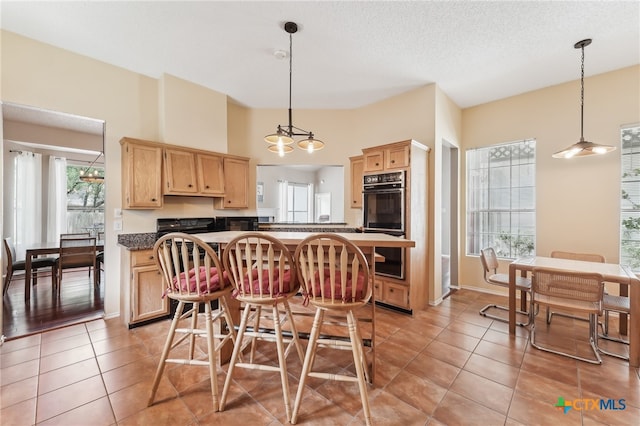 8302 Dove Valley Cv, Austin, TX 78729 - kitchen featuring light brown cabinets, dark countertops, light tile patterned floors, and decorative light fixtures