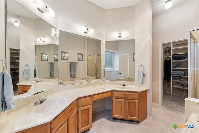 8302 Dove Valley Cv, Austin, TX 78729 - bathroom with tile patterned floors, a walk in closet, a shower stall, and double vanity