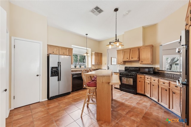8302 Dove Valley Cv, Austin, TX 78729 - kitchen featuring black appliances, a kitchen island, a kitchen bar, decorative light fixtures, and light tile patterned flooring
