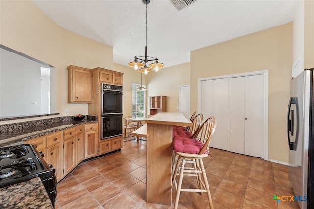 8302 Dove Valley Cv, Austin, TX 78729 - kitchen featuring black appliances, a kitchen breakfast bar, pendant lighting, a textured ceiling, and light tile patterned floors