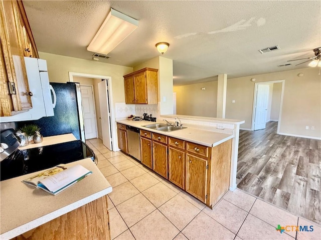 3807 Sunflower Dr, Killeen, TX 76542 - kitchen with stainless steel dishwasher, a textured ceiling, a peninsula, brown cabinetry, and range with electric stovetop