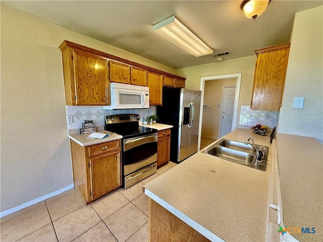 3807 Sunflower Dr, Killeen, TX 76542 - kitchen featuring stainless steel appliances, decorative backsplash, brown cabinetry, a textured wall, and a textured ceiling
