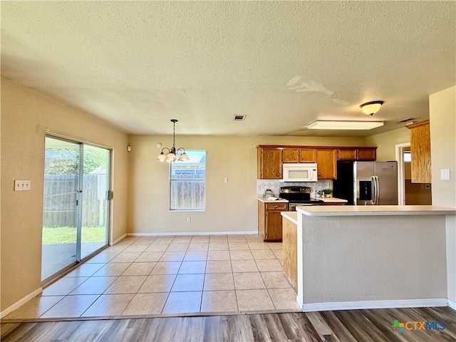 3807 Sunflower Dr, Killeen, TX 76542 - kitchen with appliances with stainless steel finishes, brown cabinets, a textured ceiling, a chandelier, and light countertops