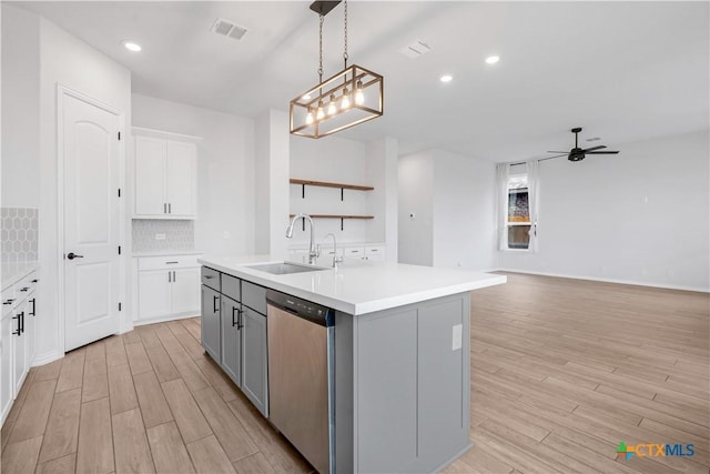 kitchen with stainless steel dishwasher, sink, a kitchen island with sink, gray cabinetry, and ceiling fan with notable chandelier