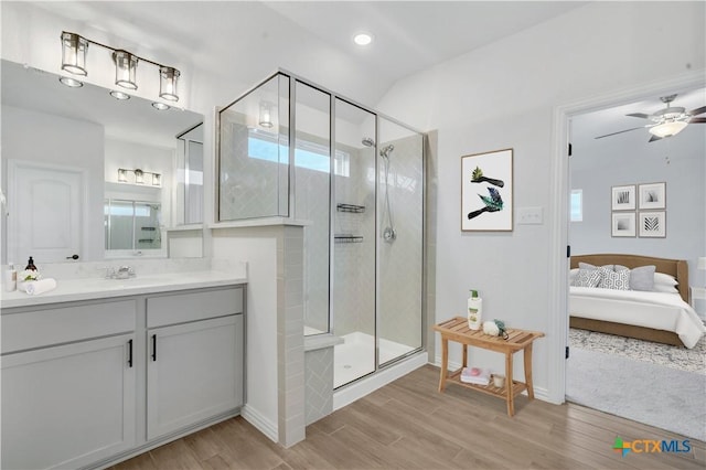 bathroom with a shower with shower door, vanity, and ceiling fan