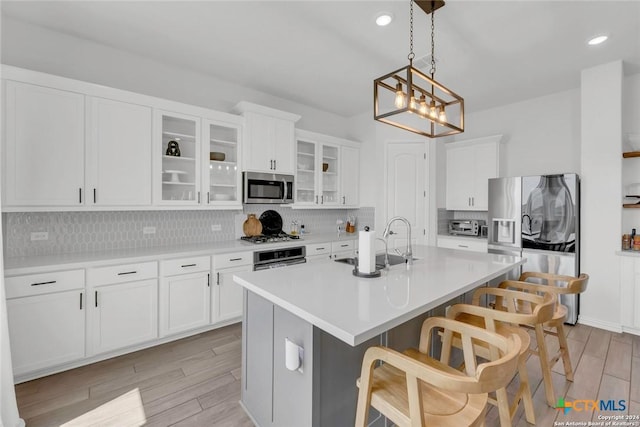 kitchen with sink, white cabinetry, appliances with stainless steel finishes, and an island with sink