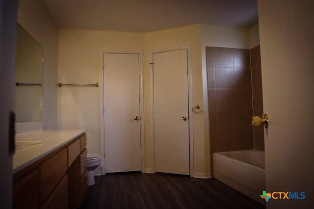 full bathroom with wood-type flooring, toilet, tiled shower / bath, and vanity