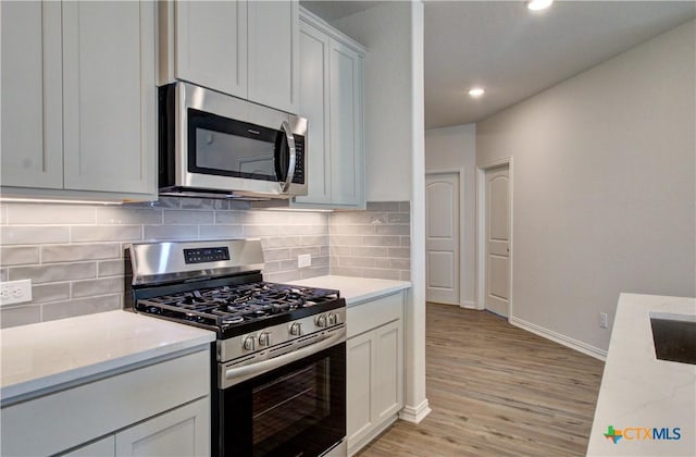 2588 Gideon Ln, New Braunfels, TX 78130 - kitchen featuring stainless steel appliances, light wood-style flooring, recessed lighting, decorative backsplash, and light stone countertops