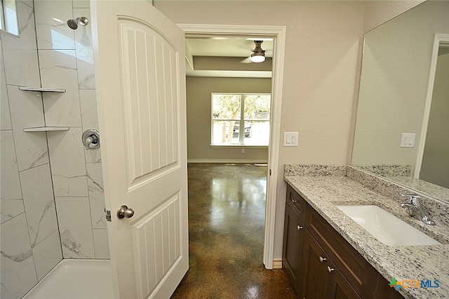 bathroom featuring vanity, a tile shower, and concrete floors