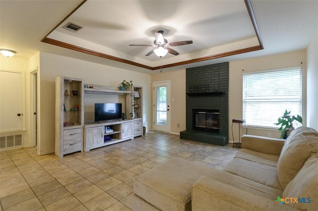 408 Sterling Manor Ct, Temple, TX 76502 - living room featuring a raised ceiling, a ceiling fan, a brick fireplace, and light tile patterned floors