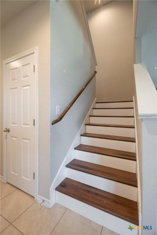 staircase with baseboards and tile patterned flooring