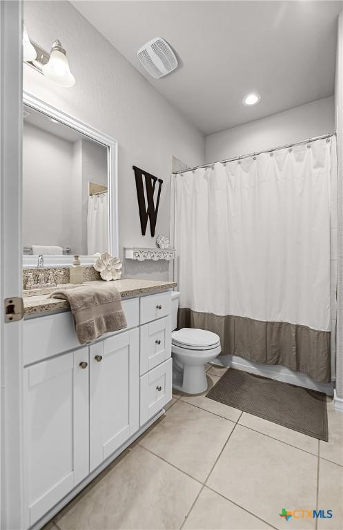 full bathroom with vanity, tile patterned floors, toilet, and visible vents