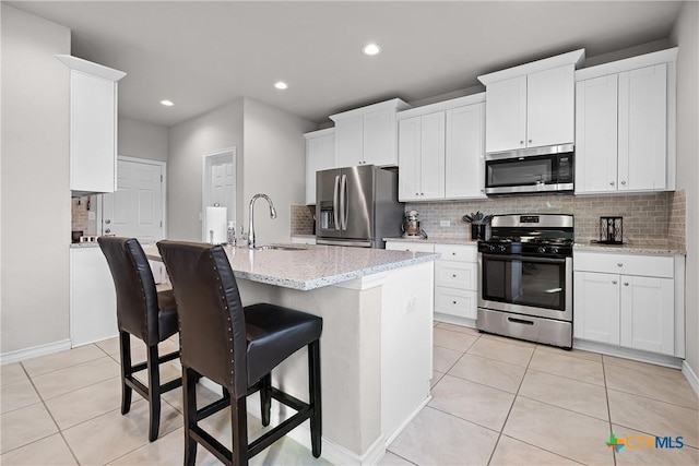 kitchen featuring a sink, tasteful backsplash, appliances with stainless steel finishes, and light tile patterned flooring