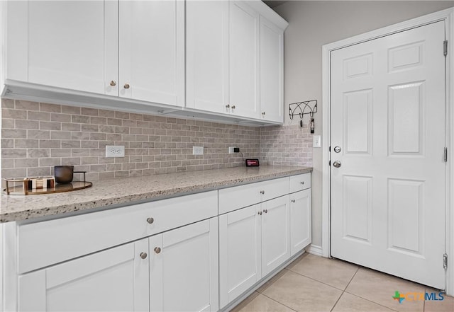 kitchen with light tile patterned flooring, backsplash, white cabinetry, and light stone counters
