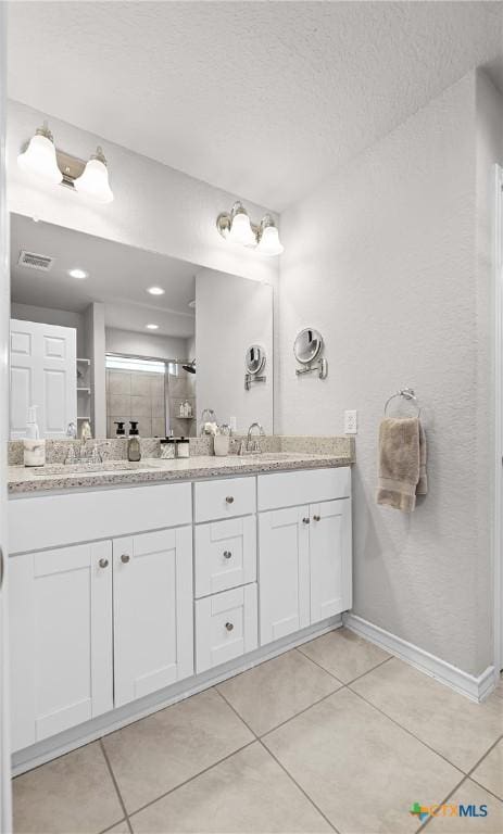 bathroom with double vanity, visible vents, tile patterned floors, and a sink