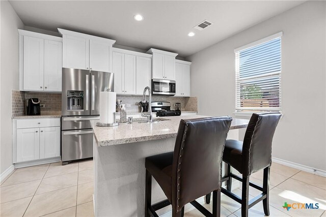 kitchen with light tile patterned floors, visible vents, a breakfast bar, a sink, and appliances with stainless steel finishes