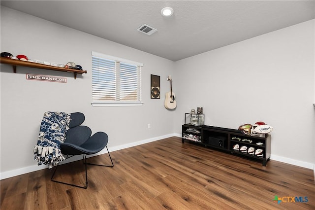sitting room with visible vents, baseboards, a textured ceiling, and wood finished floors