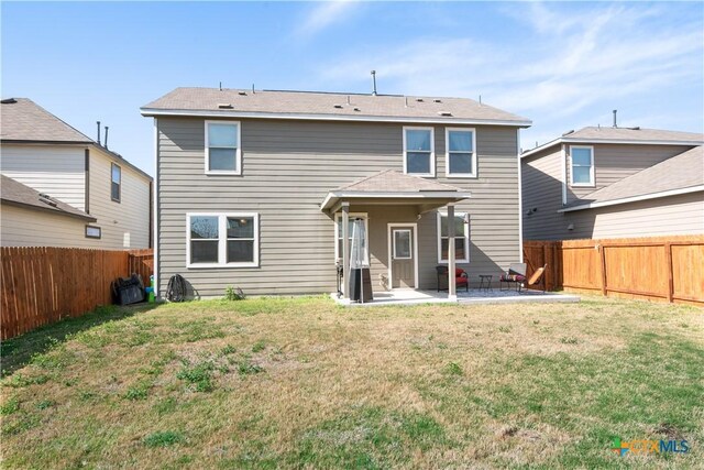 rear view of property with a patio, a lawn, and a fenced backyard