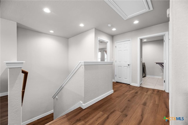 hallway with an upstairs landing, recessed lighting, baseboards, and wood finished floors