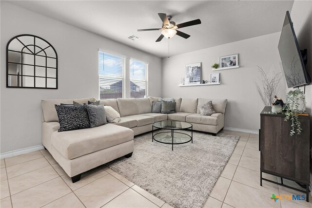 living room with light tile patterned flooring, a ceiling fan, visible vents, and baseboards