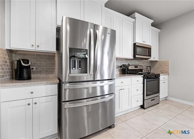 kitchen featuring tasteful backsplash, appliances with stainless steel finishes, light tile patterned flooring, and white cabinetry