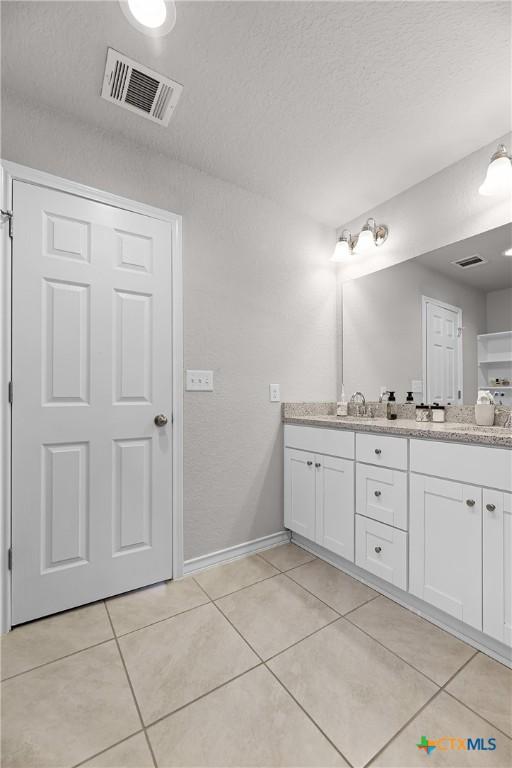 bathroom with double vanity, visible vents, baseboards, and tile patterned flooring