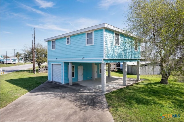 raised beach house with a front lawn, a carport, and concrete driveway