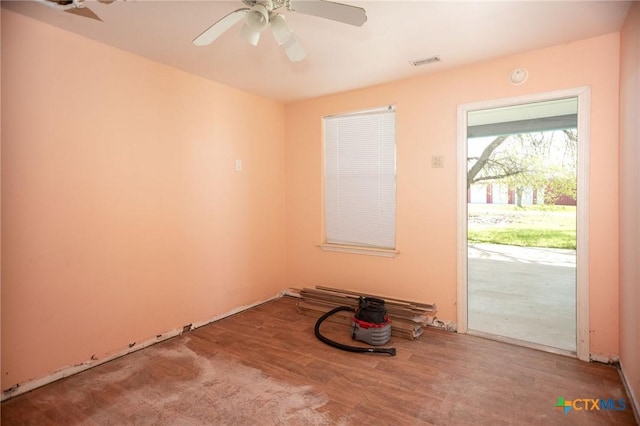 spare room with a ceiling fan, visible vents, and wood finished floors