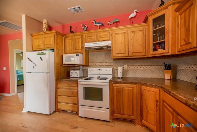 kitchen featuring glass insert cabinets, white appliances, under cabinet range hood, and visible vents