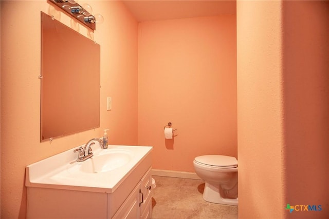 half bathroom featuring toilet, baseboards, and vanity