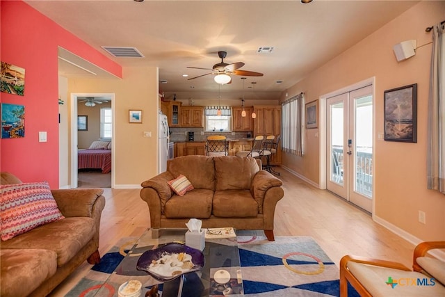 living area with french doors, light wood-type flooring, visible vents, and baseboards