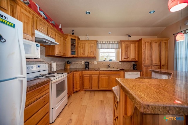 kitchen featuring under cabinet range hood, white appliances, a sink, light wood-type flooring, and tasteful backsplash