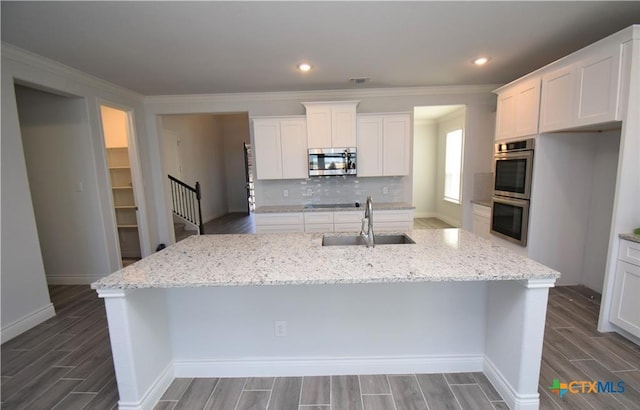 kitchen featuring white cabinetry, sink, light stone countertops, an island with sink, and appliances with stainless steel finishes