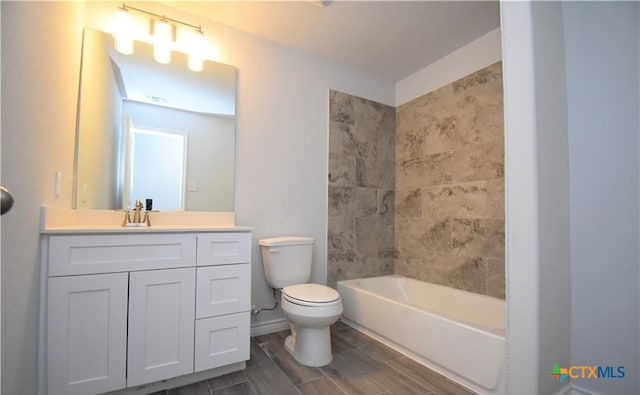 full bathroom featuring tiled shower / bath, vanity, and toilet