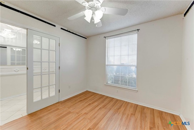 unfurnished room featuring ceiling fan, a textured ceiling, and light wood-type flooring