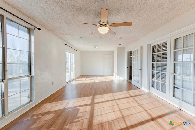 empty room with a textured ceiling, light hardwood / wood-style flooring, and ceiling fan