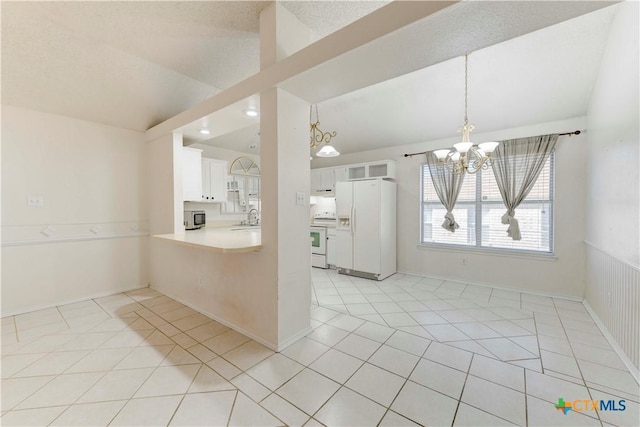 kitchen featuring white appliances, sink, an inviting chandelier, white cabinets, and lofted ceiling