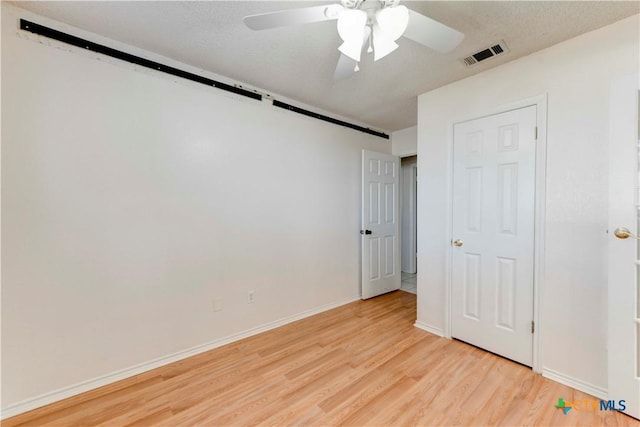 unfurnished bedroom featuring a textured ceiling, light hardwood / wood-style floors, and ceiling fan