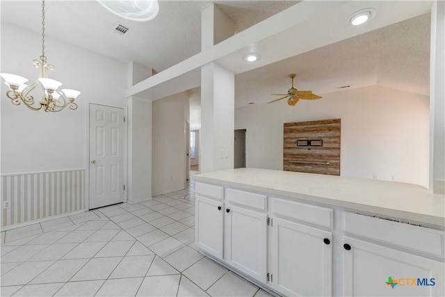 kitchen featuring white cabinetry, lofted ceiling, a textured ceiling, decorative light fixtures, and ceiling fan with notable chandelier