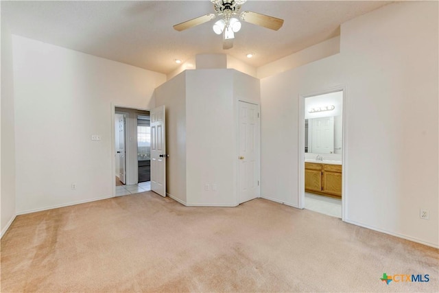 unfurnished bedroom featuring light carpet, ensuite bathroom, ceiling fan, and sink