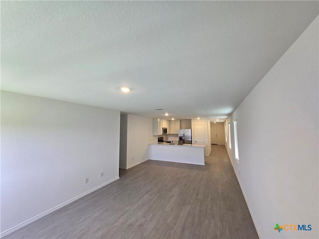 209 Tugboat Annie Way, Jarrell, TX 76537 - unfurnished living room with dark wood finished floors, baseboards, a textured ceiling, and recessed lighting